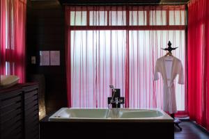 a bathroom with a sink and red curtains at Risasinee Spa & Resort in Nan