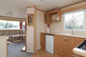 cocina con armarios de madera y sala de estar. en The Nest - Family friendly caravan nr Glastonbury & Street, en Somerton