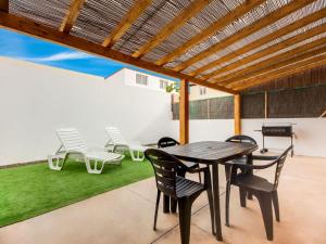 un patio con mesa de madera, sillas y césped en Casa Aloe, en Corralejo