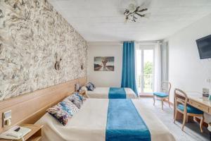 una camera d'albergo con 2 letti e una scrivania di Contact Hôtel Limoges - HOTEL DES DEUX MOULINS a Limoges