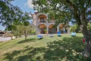 une maison avec une cour dotée de chaises et d'un arbre dans l'établissement Agriturismo Barbicate, à Saturnia