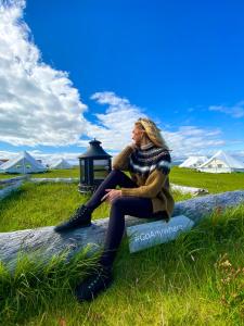 a woman sitting on a rock in the grass at Camp Boutique in Gaulverjabær