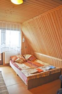 a bed in a room with a wooden wall at Dom Wczasowy Dwa Światy in Bukowina Tatrzańska
