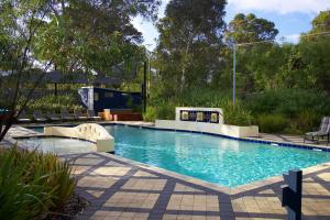 a swimming pool in a yard with chairs and trees at Leeuwin Apartments in Margaret River Town