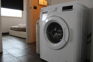 a white washing machine in a room with a bed at Open Land Holiday House in Fiumefreddo di Sicilia