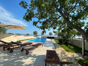 a swimming pool with two benches and an umbrella at Holiday House Laura in Vir