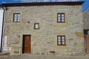 un edificio de piedra con puerta y 4 ventanas en Casa do Palheiro, en Miranda do Douro