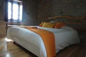 1 dormitorio con 1 cama blanca grande con manta naranja en Casa do Palheiro, en Miranda do Douro