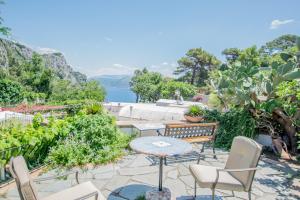 eine Terrasse mit Stühlen und Tisch und Blick auf das Wasser in der Unterkunft Appartamento immerso nel verde in Capri + 3 Fotos