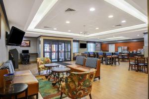 a waiting room with tables and chairs and a tv at La Quinta Inn & Suites Casino and Bar by Wyndham Glendive in Glendive