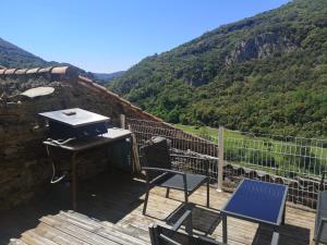 a grill and chairs on a wooden deck with a mountain at Les Citounelles in Citou
