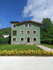 a large green house with yellow flowers in front of it at Hotel Els Avets in Camprodon