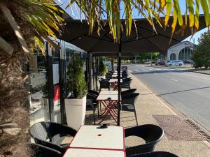 une rangée de tables et de chaises sous un parapluie sur un trottoir dans l'établissement La Locomotive, à Issoudun