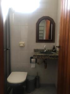 y baño con aseo, lavabo y espejo. en Durma com o barulho do mar!, en Florianópolis