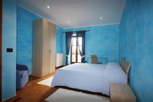 a blue bedroom with a white bed and a window at B&B Linu Ruiu in Santu Lussurgiu