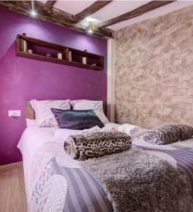 2 Betten in einem Zimmer mit lila Wänden in der Unterkunft Loft "Elegante" Lila in Ubrique