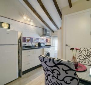 a kitchen with a refrigerator and a table with a chair at El Estudio Lila de Ubrique in Ubrique
