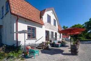 a building with tables and umbrellas in front of it at Mejeriet Stenkyrka in Tingstäde