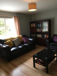 uma sala de estar com um sofá de couro preto e uma mesa em teach donal og em Falcarragh