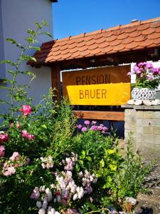 a sign for a pension broker in a garden of flowers at Pension Bauer in Ebern