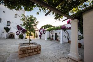a courtyard with white buildings and purple flowers at Masseria Parco di Castro in Montalbano