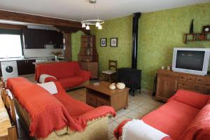 een woonkamer met rode banken en een televisie bij El Mirador del Alberche III in Navaluenga