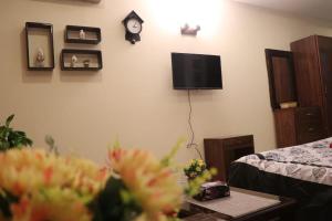 a room with a tv on a wall with flowers at Cozy Studio Apartment In Bahria town in Rawalpindi