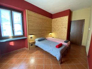 1 dormitorio con 1 cama en una habitación con paredes rojas en Locanda Reloup, en Isasca