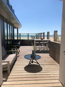 a patio with a table and a view of the beach at Beachrooms Pier 7 in Vlissingen
