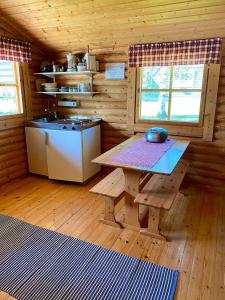 uma cozinha com uma mesa e um lavatório numa cabina em Huhtaniemen Mökkikylä em Veteli