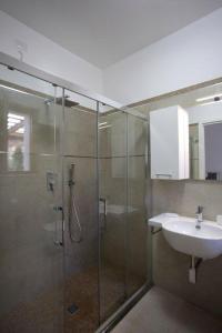 a bathroom with a glass shower and a sink at Cala Azul Residence B&B in Alghero