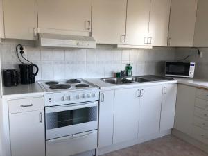 a kitchen with white cabinets and a stove and a sink at Apartment in central Kiruna 3 in Kiruna