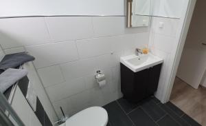 a white bathroom with a sink and a toilet at Ferienwohnung Strandjuwel am Strand in Norddeich