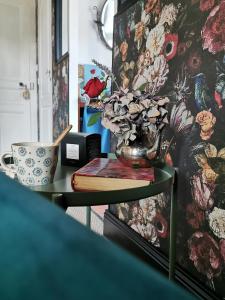 a table with a vase and a book and a cup at Quatre Chats sous un Pin in Le Thoureil