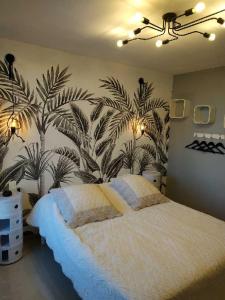 - une chambre avec un grand lit orné d'une fresque murale de palmiers dans l'établissement Appartement Rêve-Catalan 2 chambres, à Perpignan