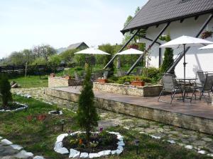 a house with a patio with umbrellas and a garden at Pensiunea Passiflora in Mănăstirea Humorului