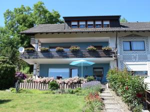 a house with a balcony with flowers and an umbrella at Apartment Rose Sasbachwalden in Sasbachwalden