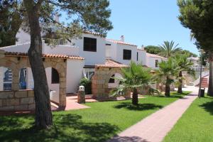 a white house with trees and a pathway at Apartaments Talayot in Cala en Blanes