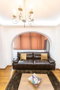 a leather couch in a living room with a chandelier at Sud Dreams Apartments in Bucharest
