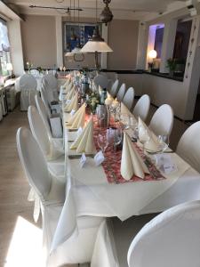a long table with white chairs and a white table cloth at Landhaus Tesperhude in Geesthacht