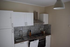 uma cozinha com armários brancos e um lavatório em La Dimora di Lalla em Lanciano
