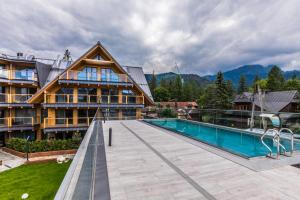 a house with a swimming pool next to a building at Luxury Apartments in Zakopane