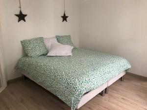 a bed in a bedroom with a green comforter and pillows at La Savane du Donjon in Rouen