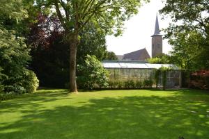 einen grünen Hof mit einem Gewächshaus und einer Kirche in der Unterkunft Fiddler's Hoorn in Zwaag