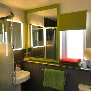uma casa de banho com um espelho verde e um lavatório em Coast Apartment em Sidmouth