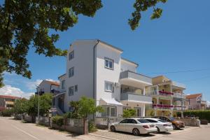 a white building with cars parked in front of it at Apartments Lovrić in Vodice