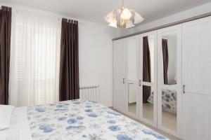 a white bedroom with a bed and a chandelier at Apartments Lovrić in Vodice