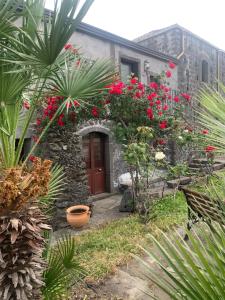 ein Steinhaus mit roten Blumen davor in der Unterkunft Villa Alessio - Case Vacanza con Piscina sull'Etna in Puntalazzo