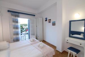a white bedroom with a bed and a tv at Sea Breeze Studios in Paleokastritsa