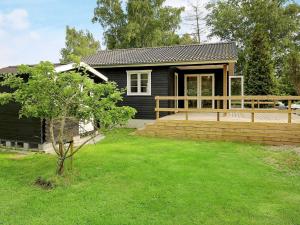 ein kleines schwarzes Haus mit einer Terrasse und einem Hof in der Unterkunft 4 person holiday home in Skibby in Skibby